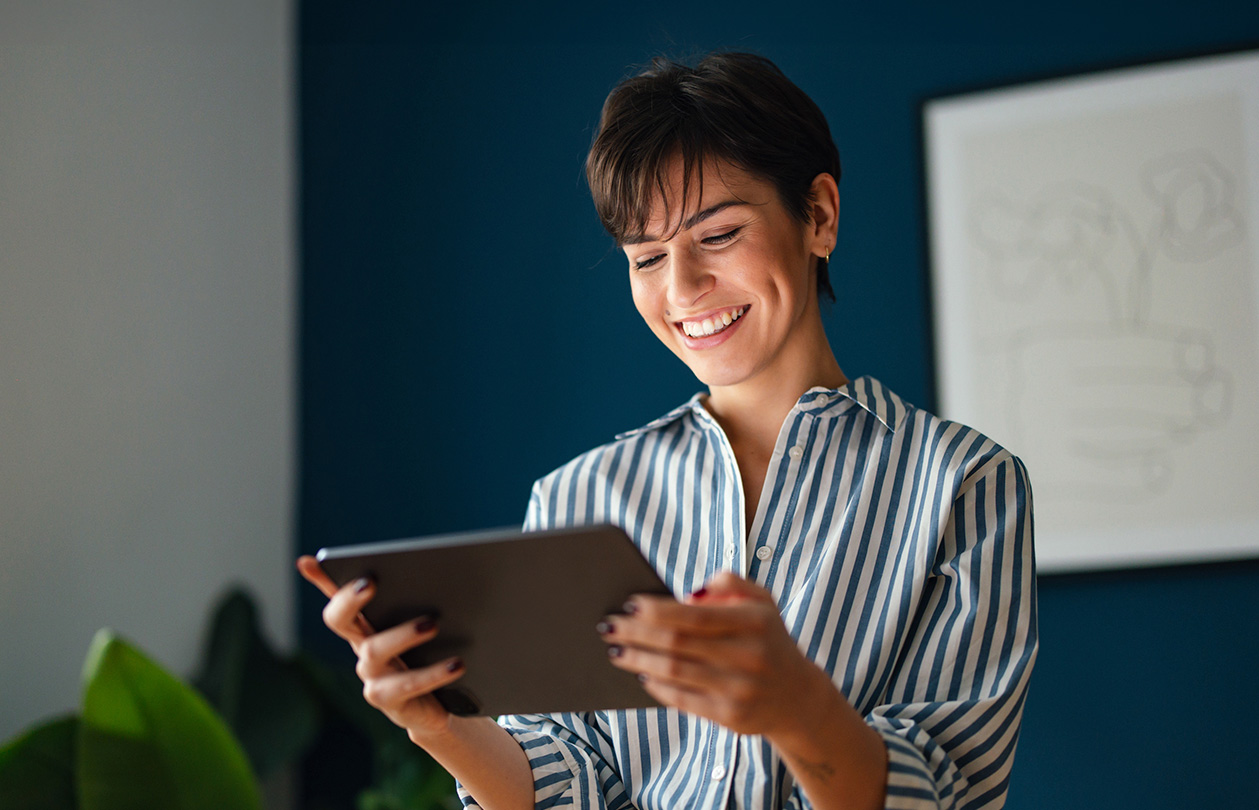 A smiling woman looking at a tablet device