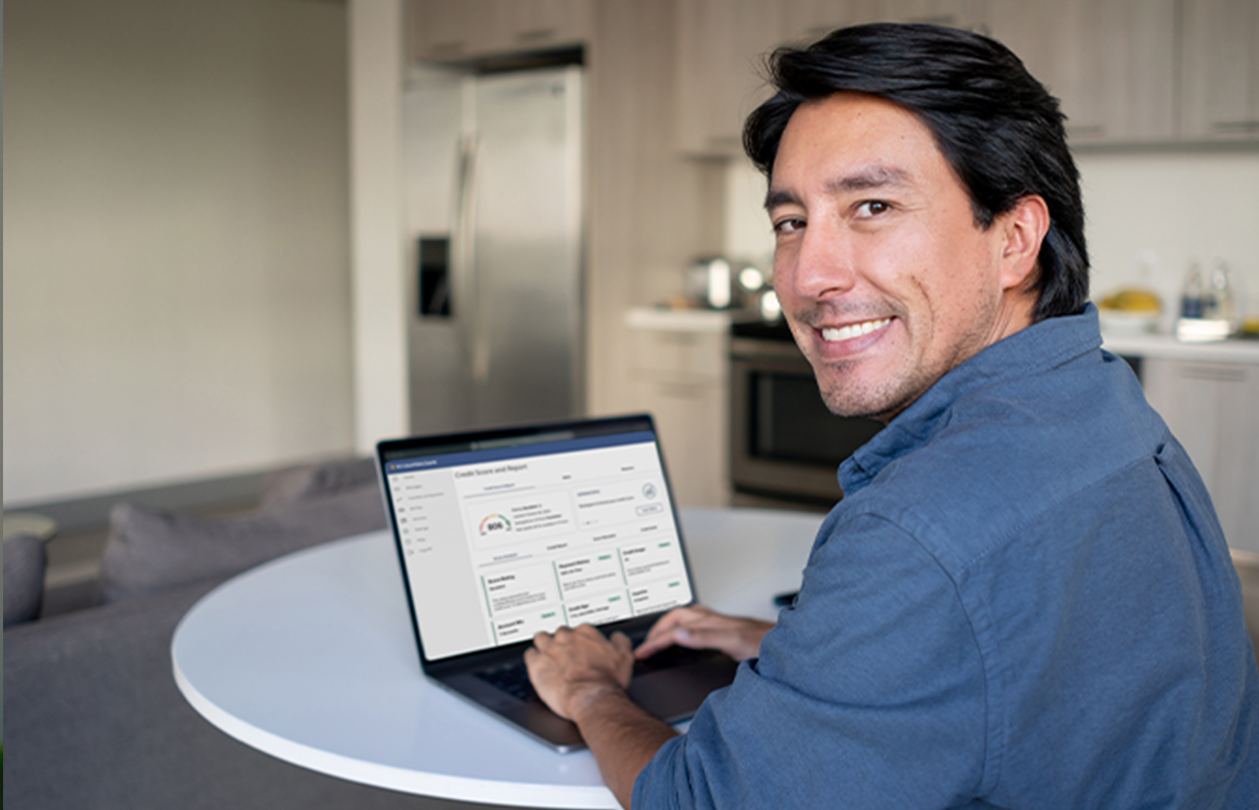 A smiling man checking his credit score on a laptop