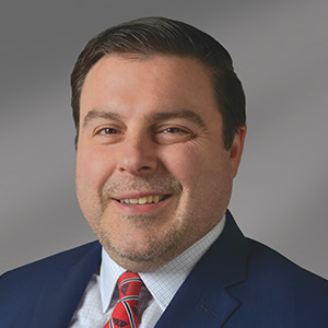 Headshot of Anthoy Cuadro, smiling professionally.